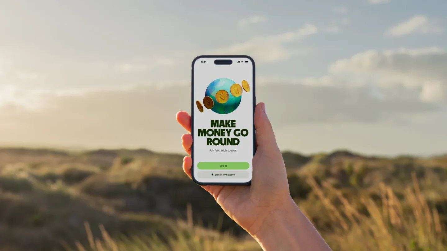 A hand holding a phone showing the Wise login screen outdoors.