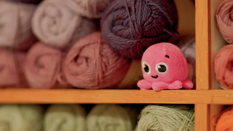An Octopus Energy mascot among balls of wool at The Fibreworks.